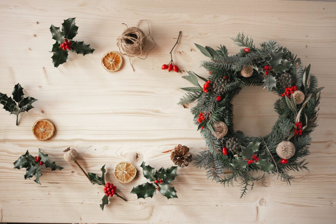 corona de navidad con elementos naturales, acebo, pino, naranjas y bayas