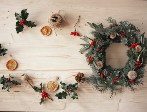 corona de navidad con elementos naturales, acebo, pino, naranjas y bayas